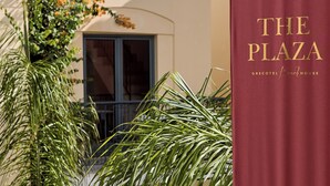 A maroon curtain with "The Plaza" and "Grecotel Beach House" text. - Grecotel Plaza Beach House (Rethymno)