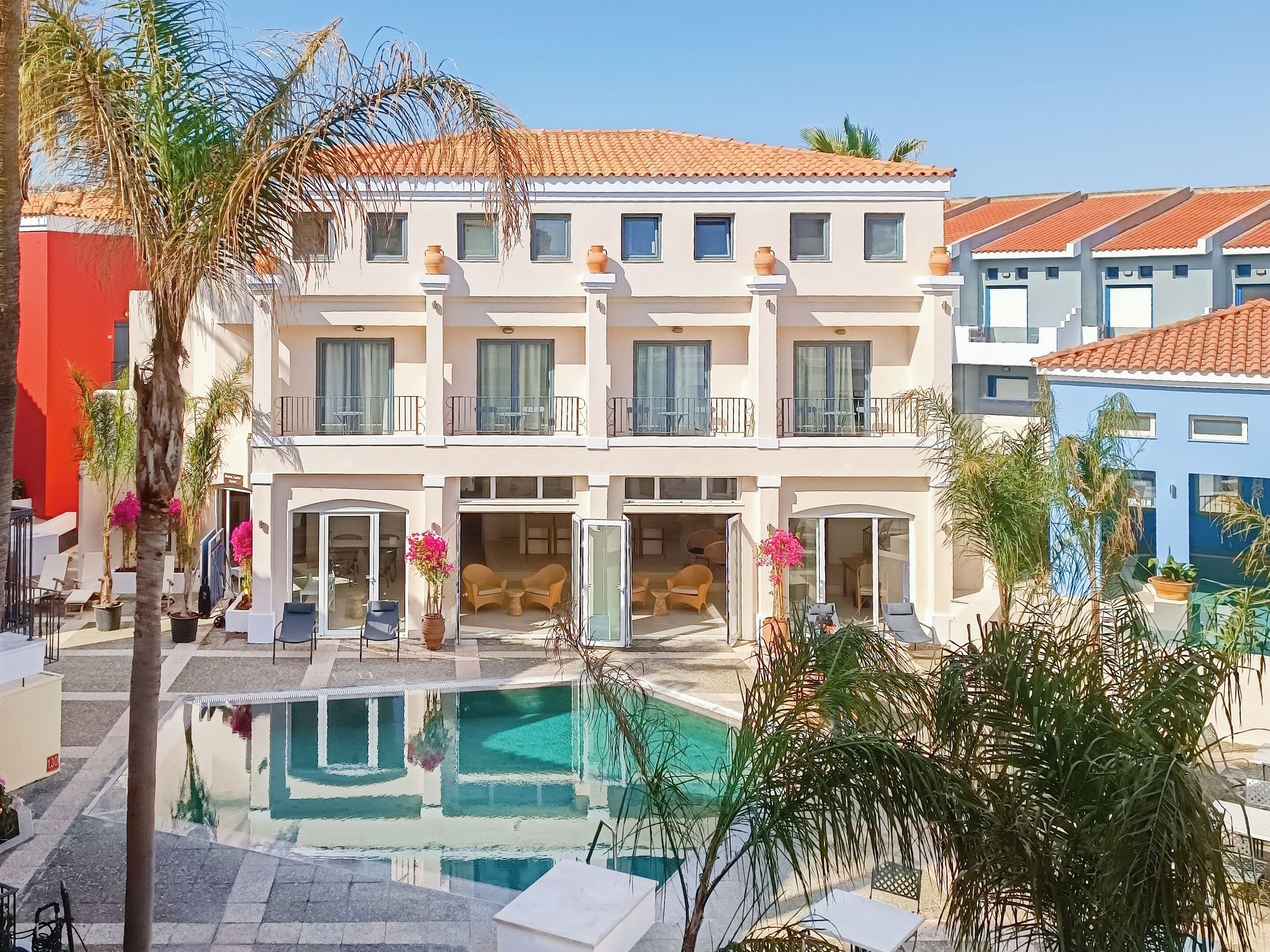 A multi-story hotel with a swimming pool, outdoor seating, and balconies.