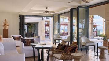 Un salon spacieux doté d’un ventilateur de plafond, de sièges confortables et offrant une vue sur la plage.