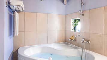 A bathroom with a bathtub, a towel rack, a showerhead, and a small window.