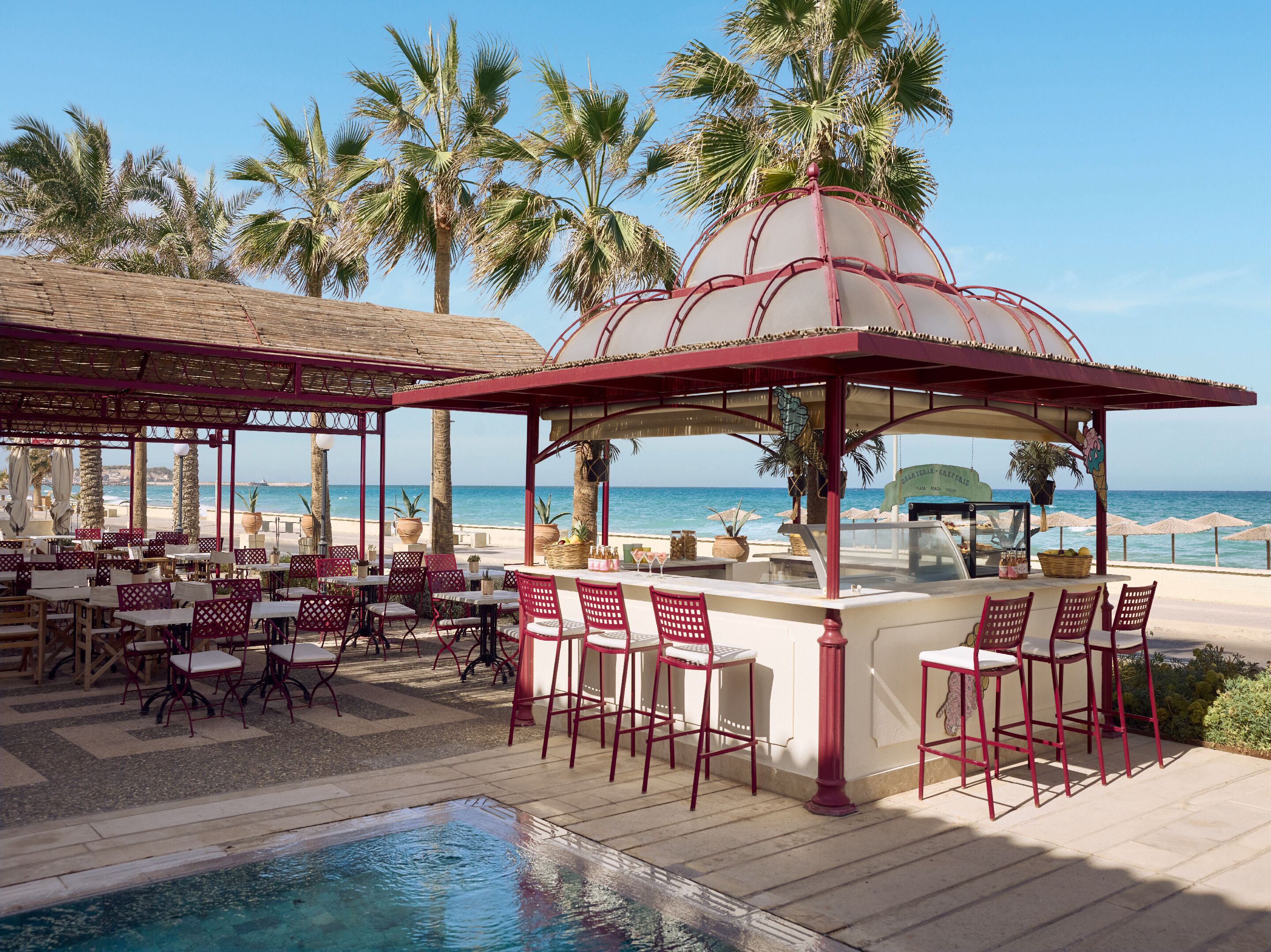 Un restaurante junto a la playa con terraza, piscina y vistas al océano.