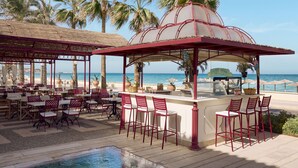 Un restaurante junto a la playa con terraza, piscina y vistas al océano.
