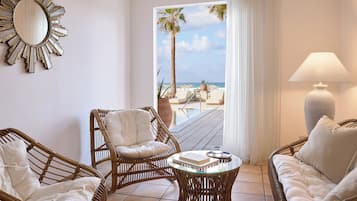 Una habitación con muebles de mimbre, una mesa redonda, un espejo grande y vista al mar.