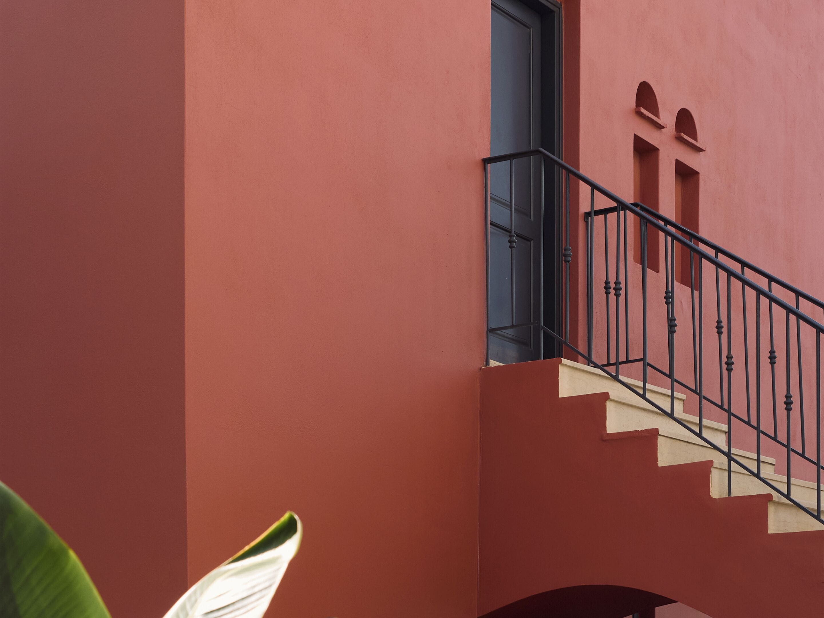 Un edificio rojo con una escalera metálica negra y una puerta.