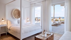 A four-poster bed with a view of a pool and beach. - Grecotel Plaza Beach House (Rethymno)