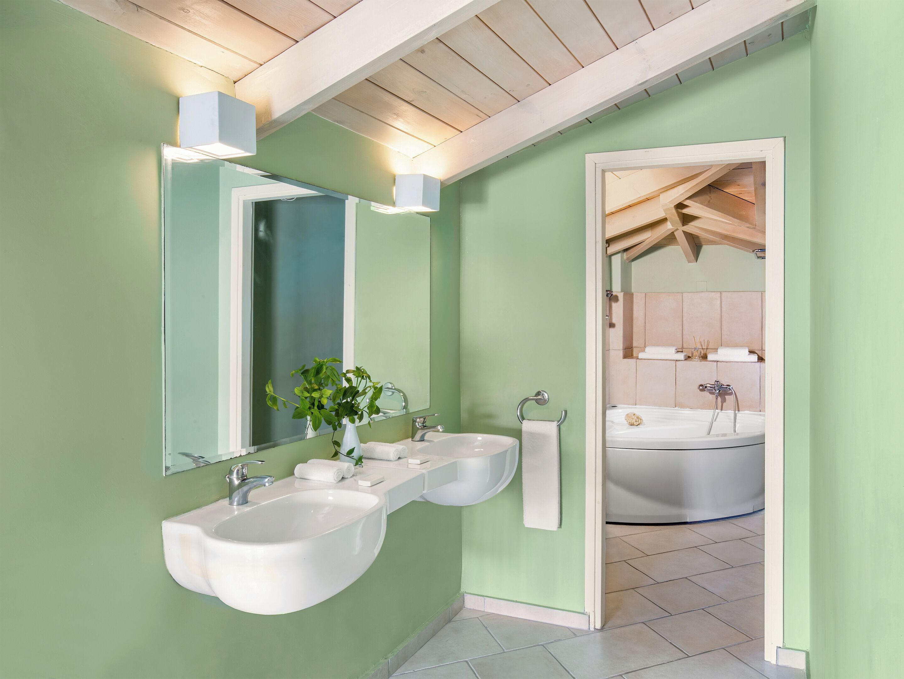 Un baño con dos lavamanos, un espejo y una bañera.