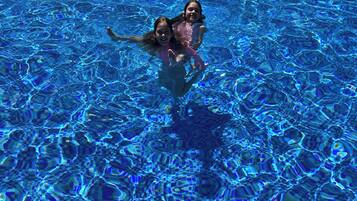 A swimming pool with clear blue water and a tiled bottom.