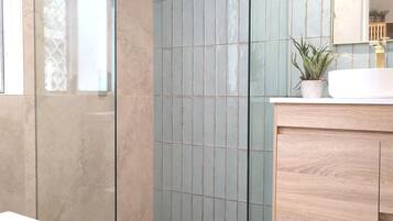 A modern bathroom with a glass shower enclosure, a white toilet, and a wooden vanity.