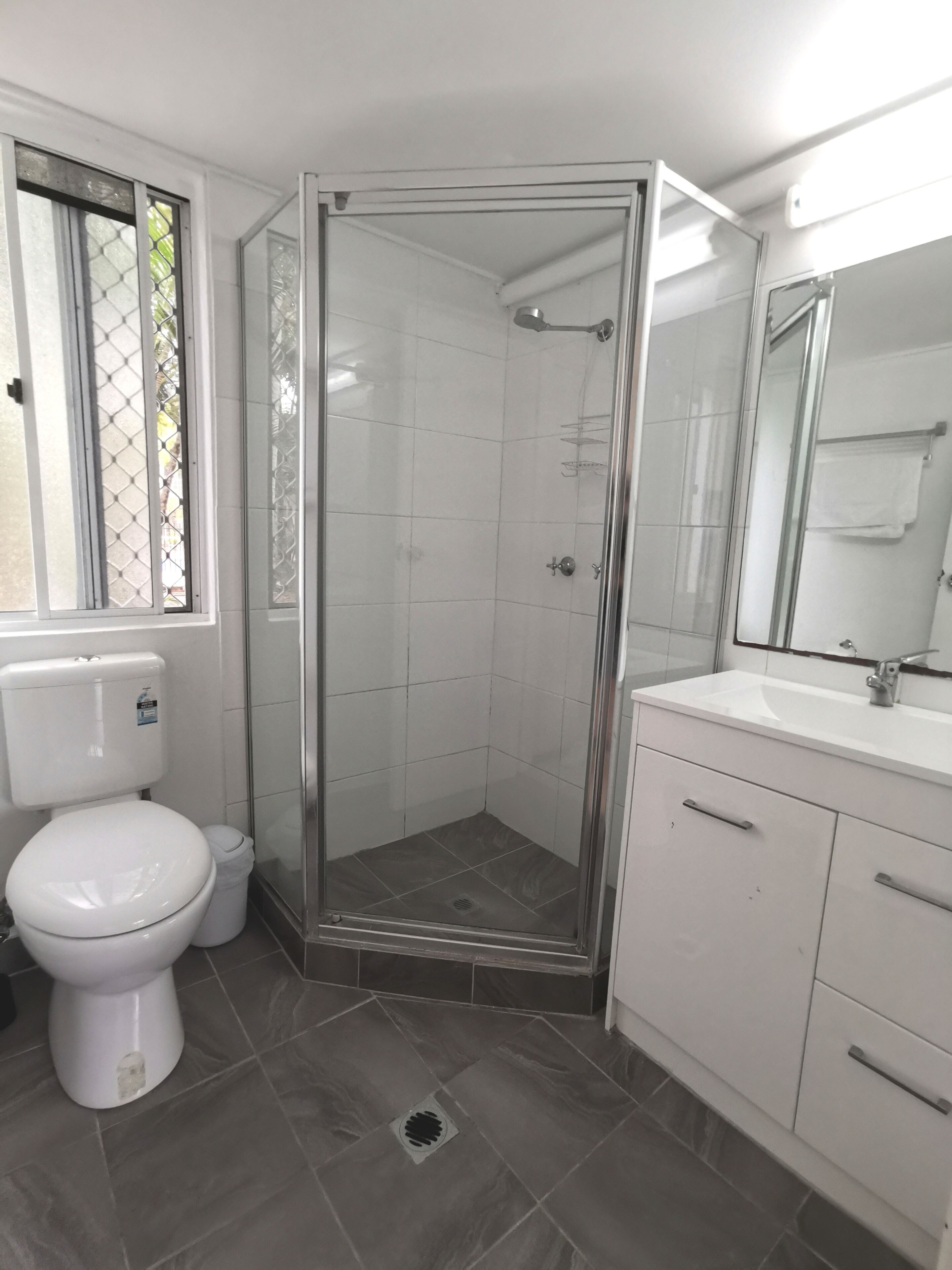 A bathroom with a glass-enclosed shower, a toilet, and a sink with a mirror.
