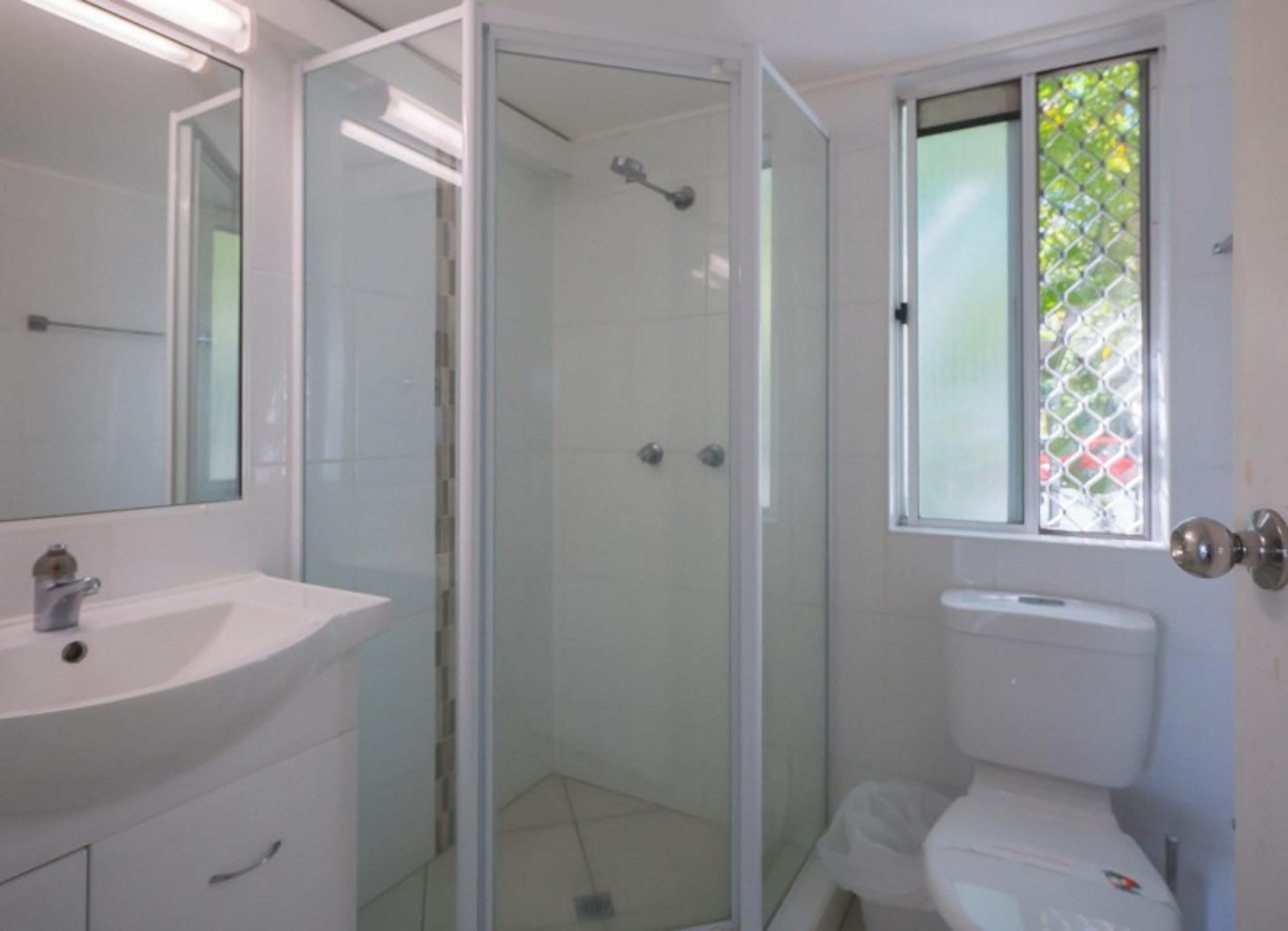 Une salle de bain avec une douche à parois de verre, un lavabo blanc et des toilettes.
