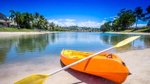 A kayak with two paddles on a sandy beach by a calm body of water. - Bay of Palms (Elanora)