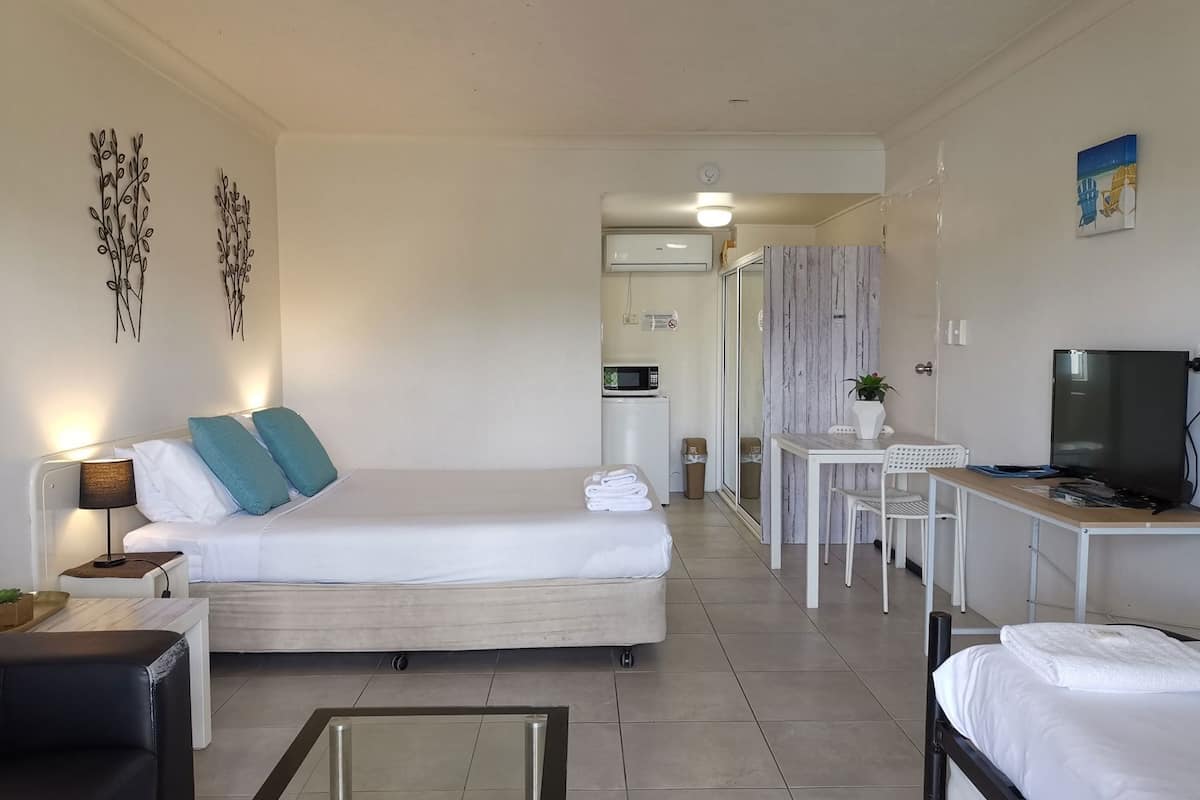A modern hotel room with a bed, desk, and TV.