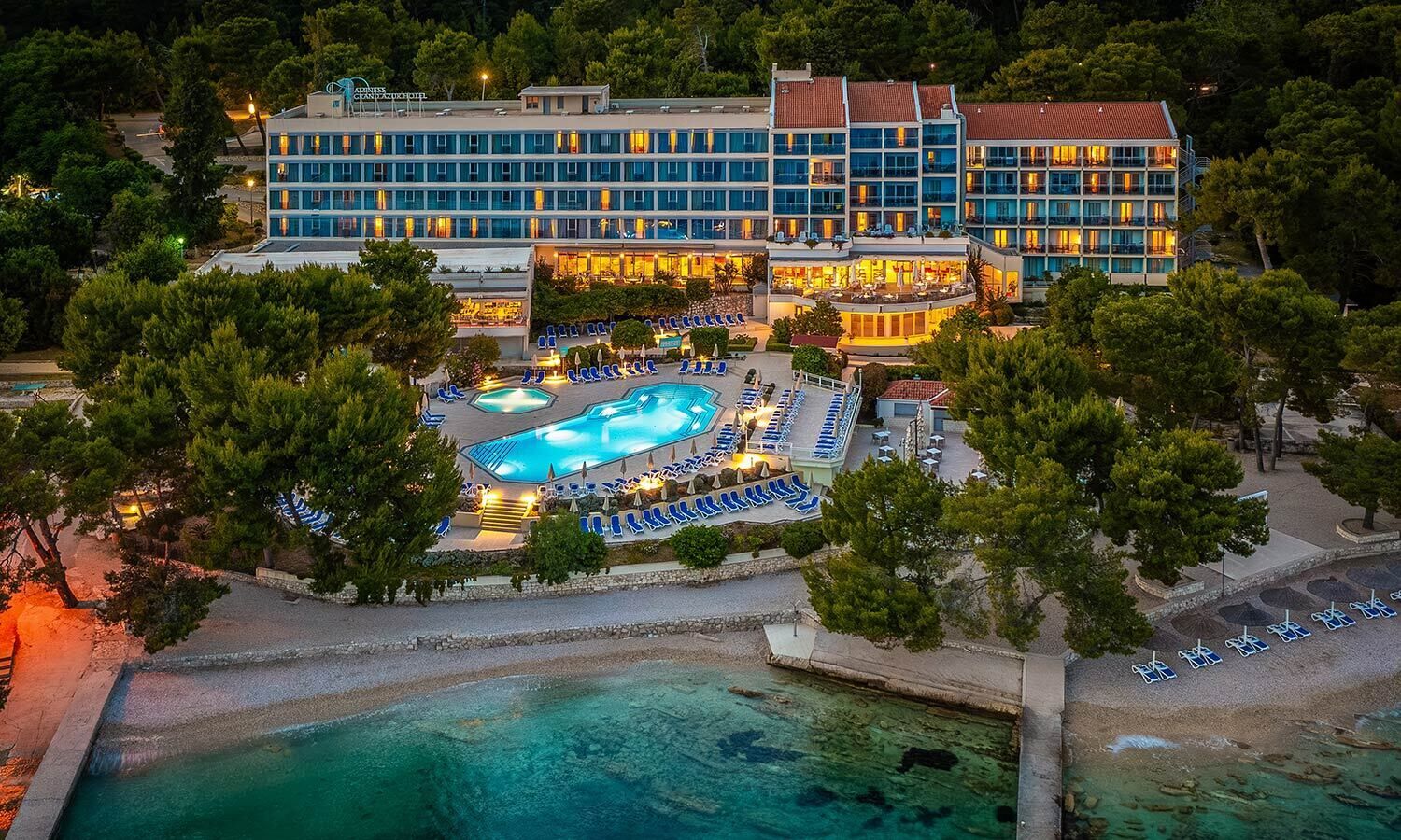 A hotel with multiple buildings, a swimming pool, and a beach area.