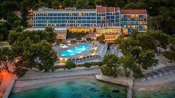 A hotel with multiple buildings, a swimming pool, and a beach area.