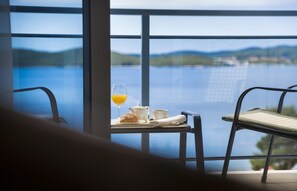 A balcony with a table set for breakfast, including a glass of orange juice, a croissant, a teapot, and a cup.