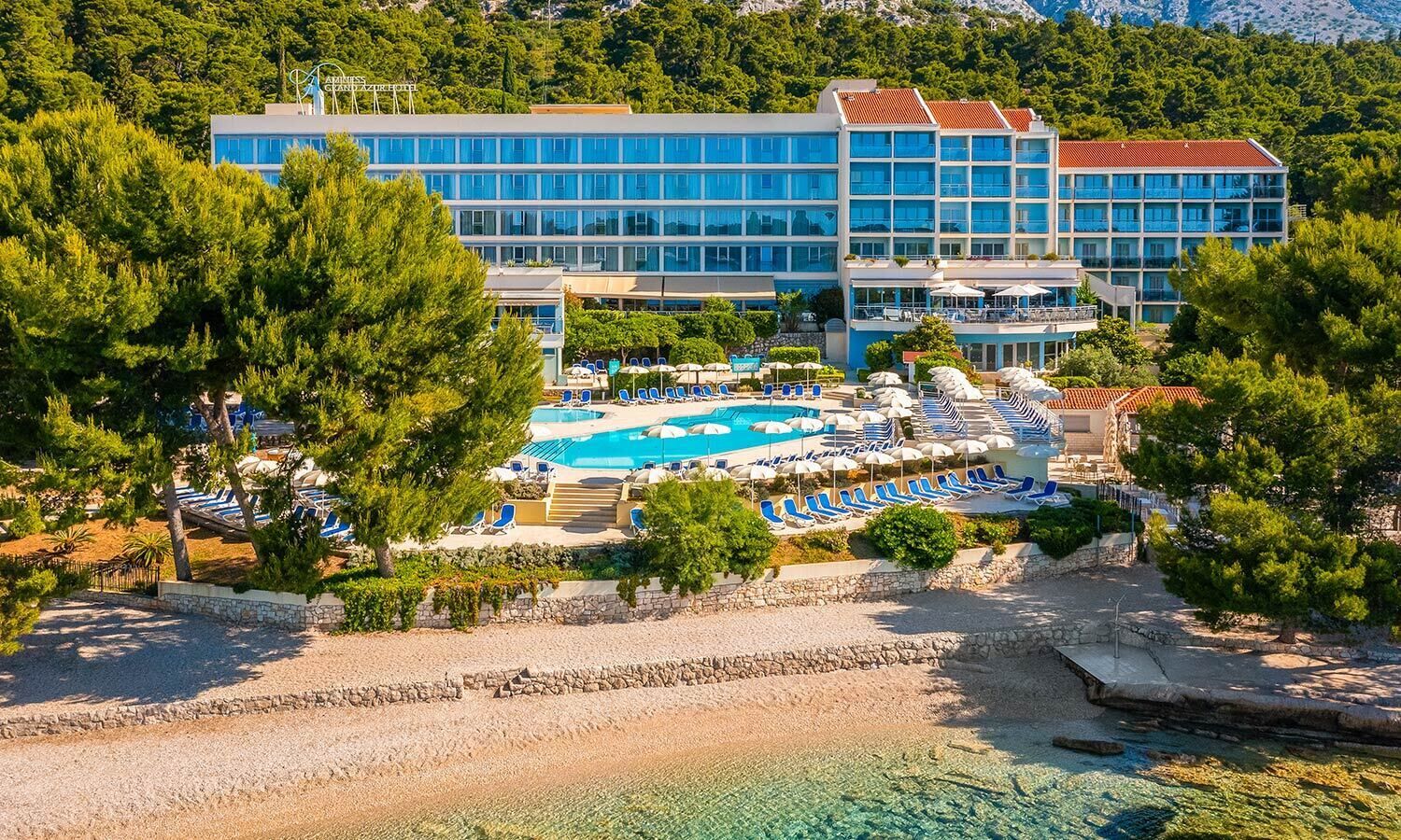 A hotel with a large pool area, multiple swimming pools, and a beach.