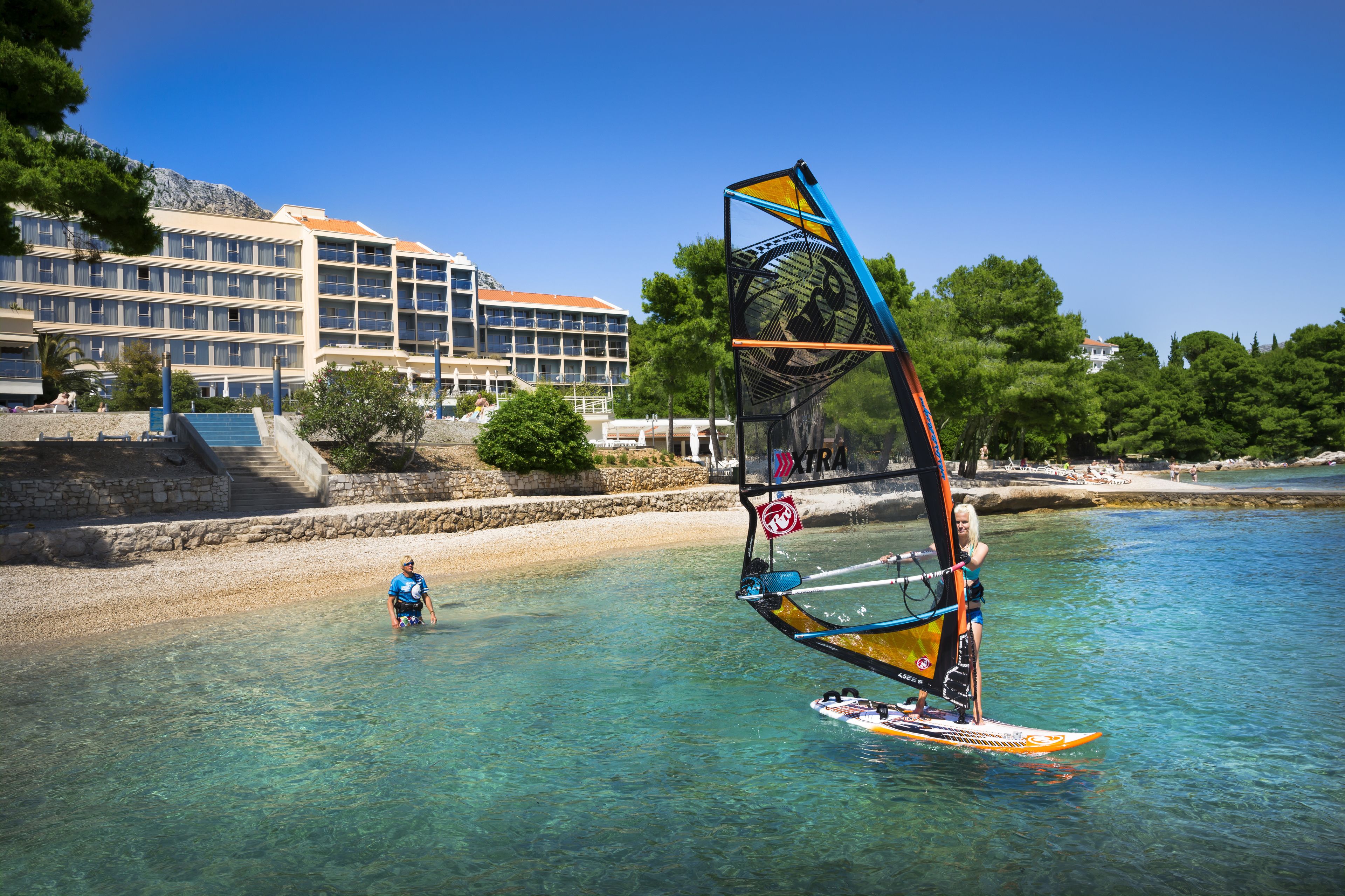 Ein Küstenhotel mit freiem Blick auf das Meer und einer nahegelegenen Windsurf-Aktivität.