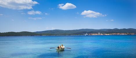 A boat on a calm, clear blue sea with a distant shoreline and mountains.