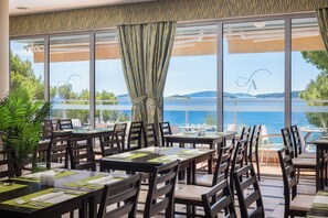 Un restaurant doté d’une terrasse offrant une vue sur un plan d’eau, avec de grandes fenêtres et un panorama sur le paysage.