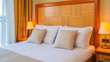 Una habitación de hotel con una cama grande, dos lámparas de noche y un cabecero de madera.