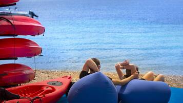 Una playa con kayaks y sillones inflables.