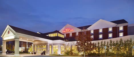A hotel with a prominent 'Hilton Garden Inn' sign, a covered entrance, and a parking lot.