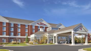 Ett Hilton Garden Inn-hotell med en fasad av tegel, en överbyggd entré och en klarblå himmel.