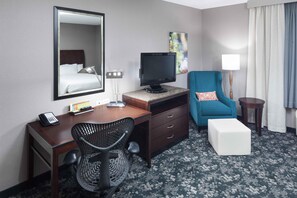 Une chambre d’hôtel équipée d’un lit, d’un bureau, d’une chaise, d’une télévision et d’une petite table avec une lampe.
