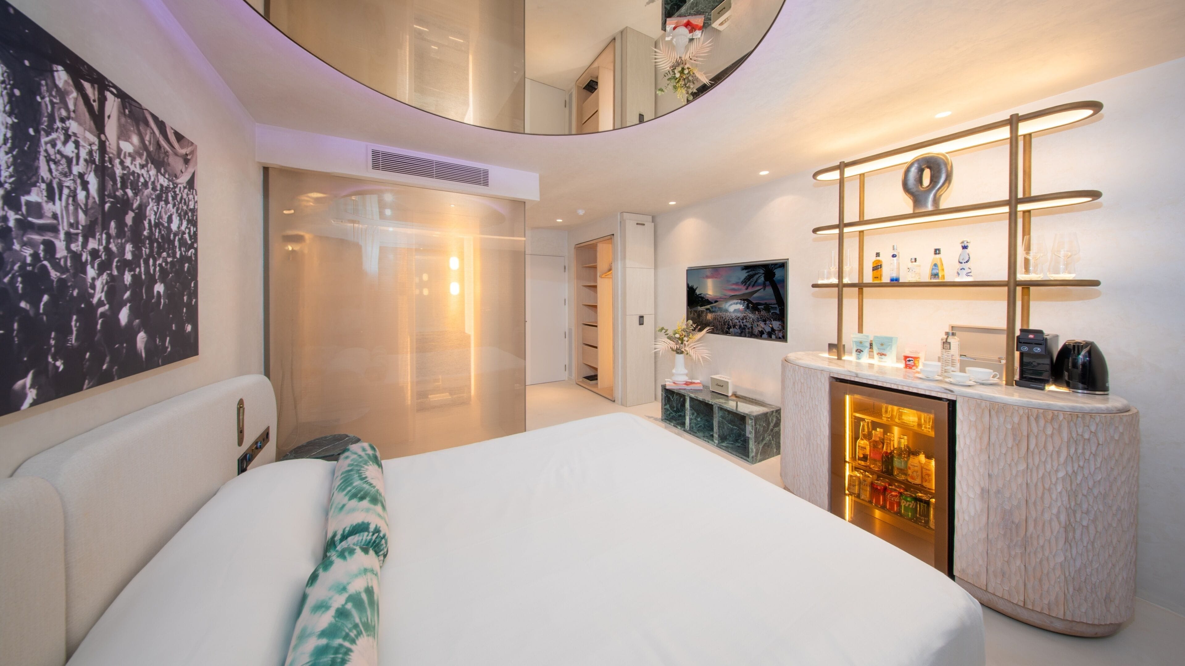 Ein modernes Hotelzimmer mit Bett, Minibar, Sitzecke und einem großen Kunstwerk an der Wand.