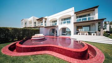 Een buitenzwembad, parasols bij het zwembad en ligstoelen