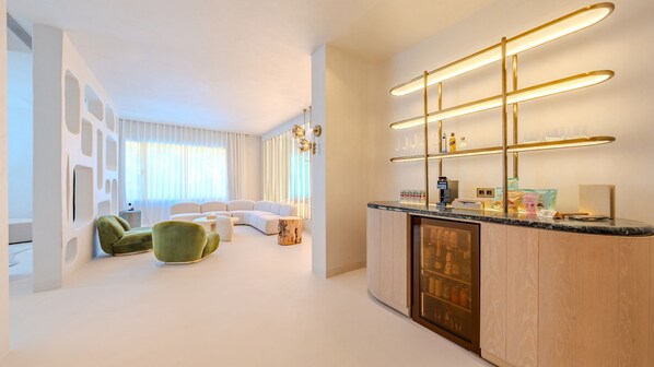 Eine moderne Küche mit Einbaukühlschrank, einer Arbeitsplatte mit Gläsern und einer Sitzecke inklusive Sofa und Stühlen.