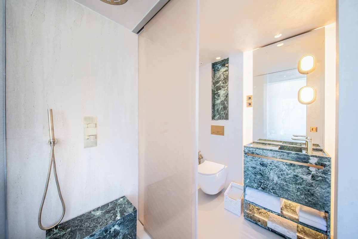 A bathroom with a shower, toilet, and a sink with a marble countertop.