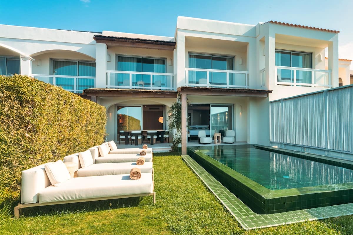A modern house with a swimming pool, a covered patio, and a white exterior.