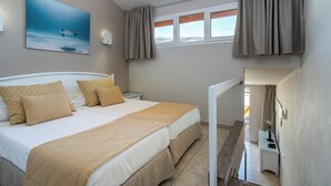 Un dormitorio con cama, mesita de noche, cortinas en la ventana y un cuadro en la pared.
