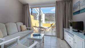 Una sala de estar moderna con un sofá, una mesa de centro de vidrio y un televisor sobre un mueble.