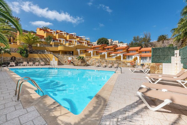 A swimming pool with lounge chairs and a stone wall.