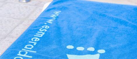 A blue towel with a white logo and text, placed on a poolside area.