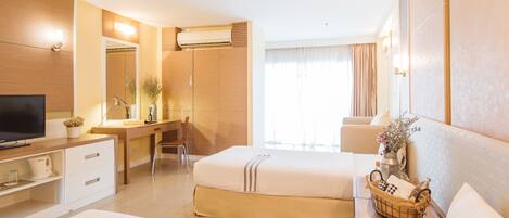Una habitación de hotel con cama, escritorio, televisor y baño.