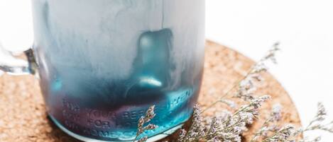 Taza de vidrio transparente con cubitos de hielo sobre un posavasos de corcho.