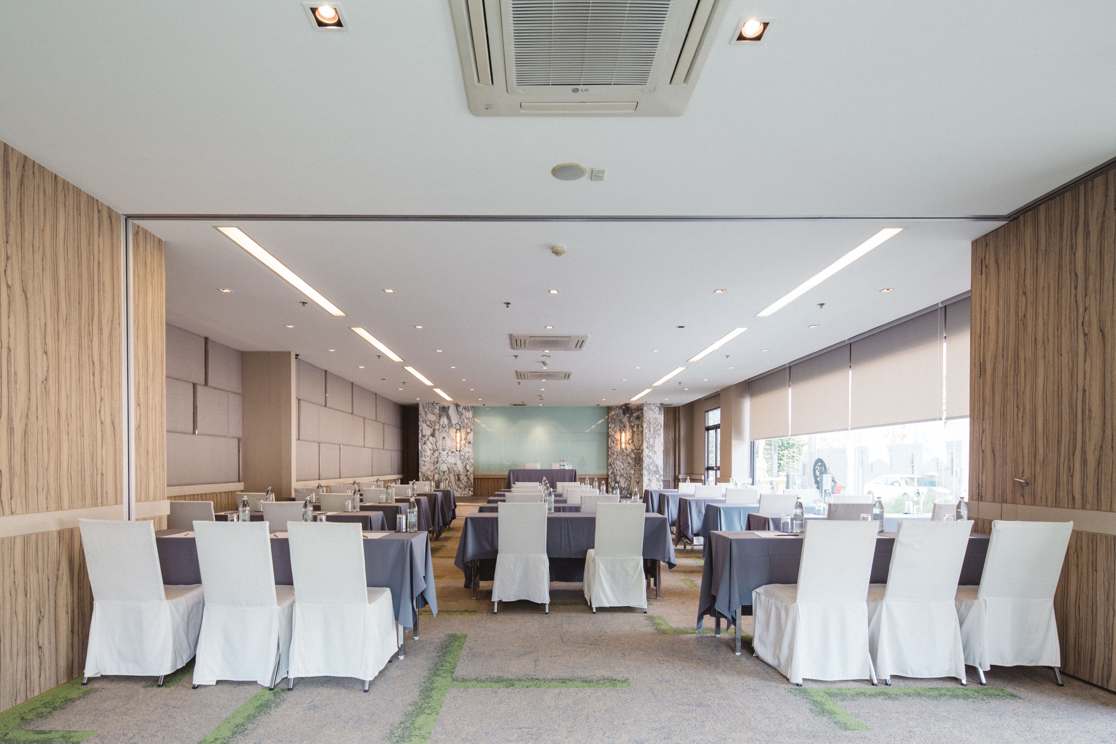 A conference room with tables and chairs, large windows, and a modern ceiling design.