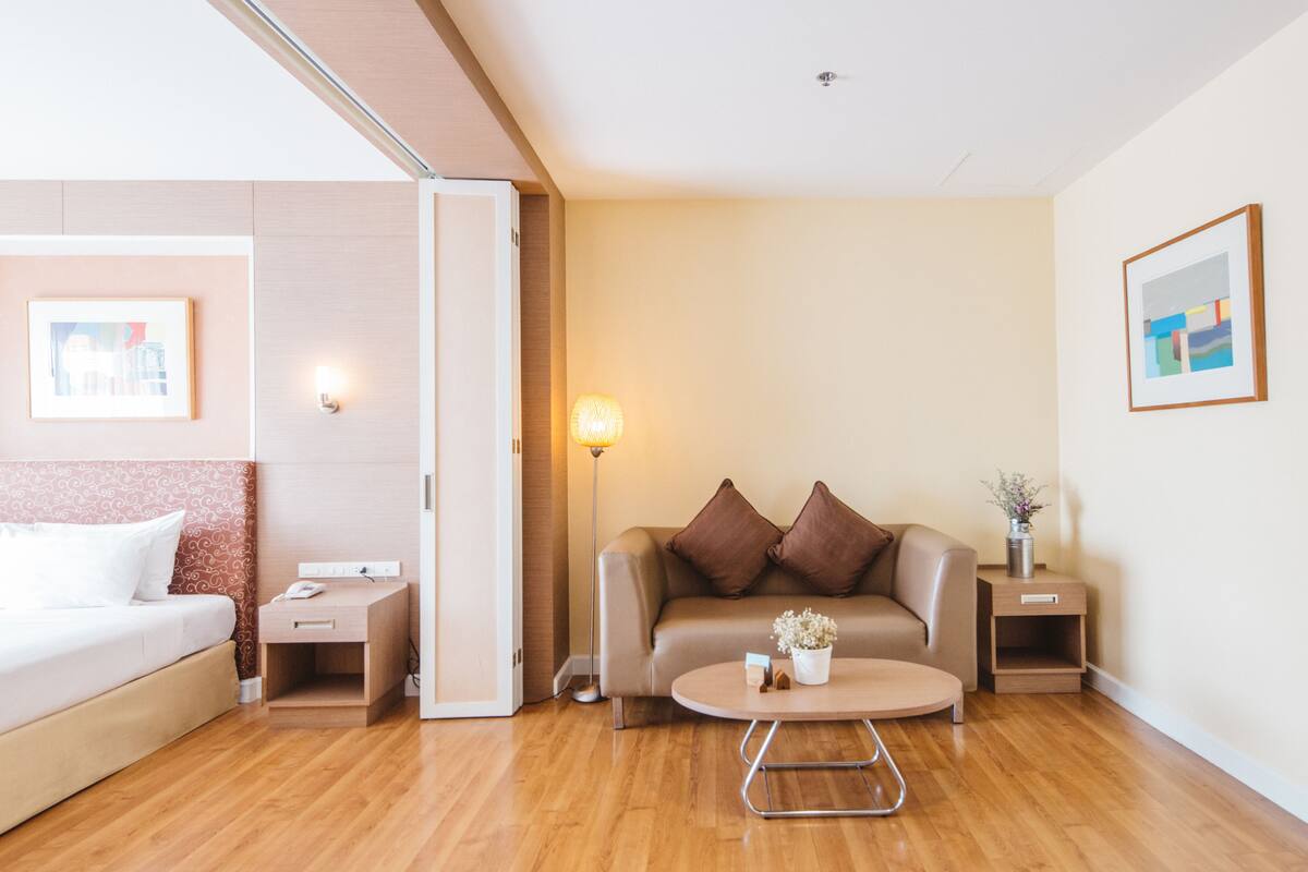 Una habitación de hotel moderna con una cama, un sofá, una mesita de centro y una mesita de noche.