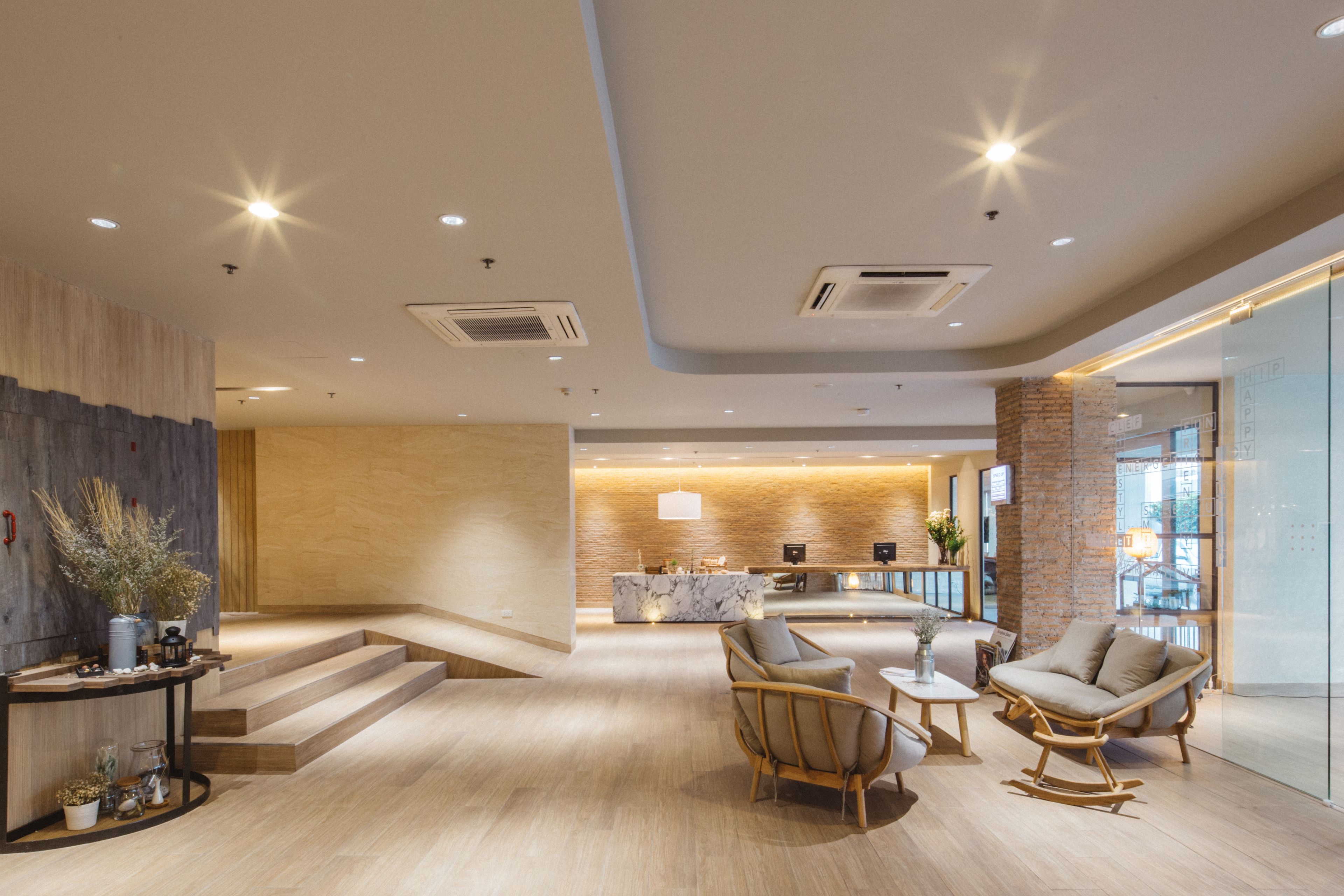 A modern lobby with a reception desk, seating area, and a staircase leading to upper floors.