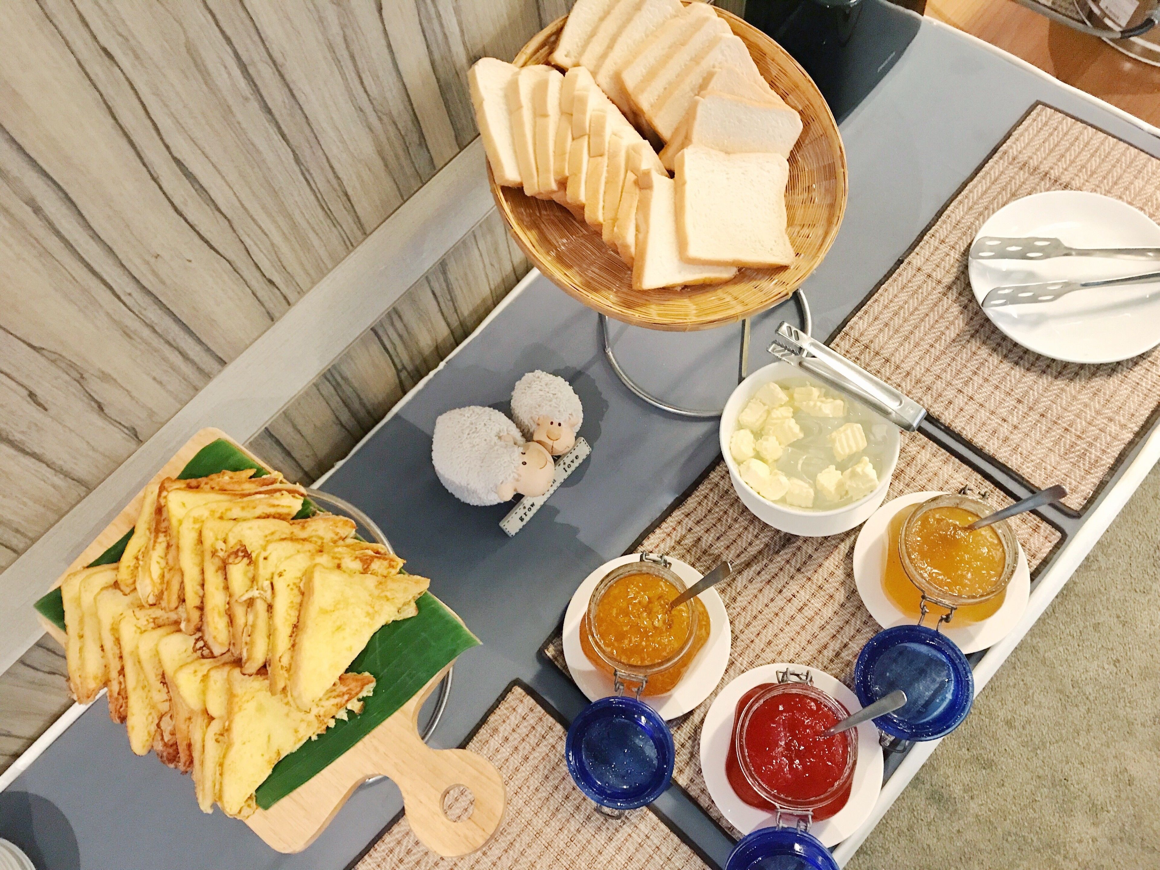 A buffet table with various food items including sliced bread, a bowl of soup, and several jars of condiments.