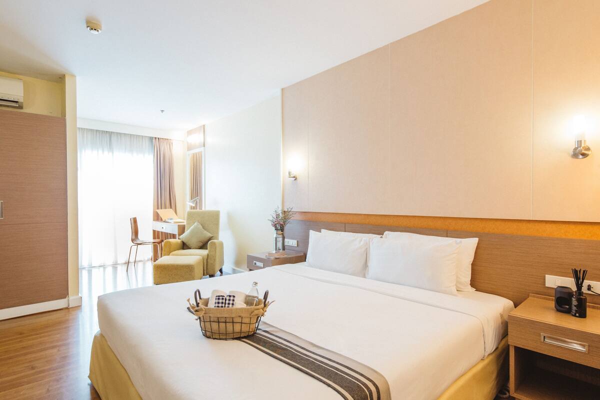 Una habitación de hotel con una cama grande, una mesita de noche y una silla.