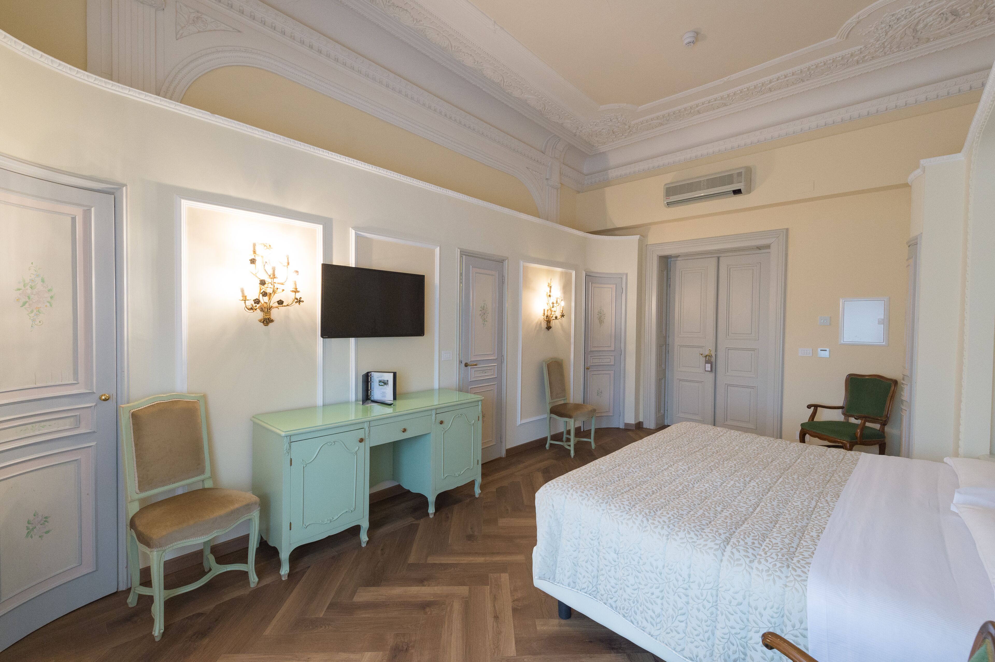 Habitación de hotel con una cama grande, un escritorio con silla, televisión y dos lámparas de pared.