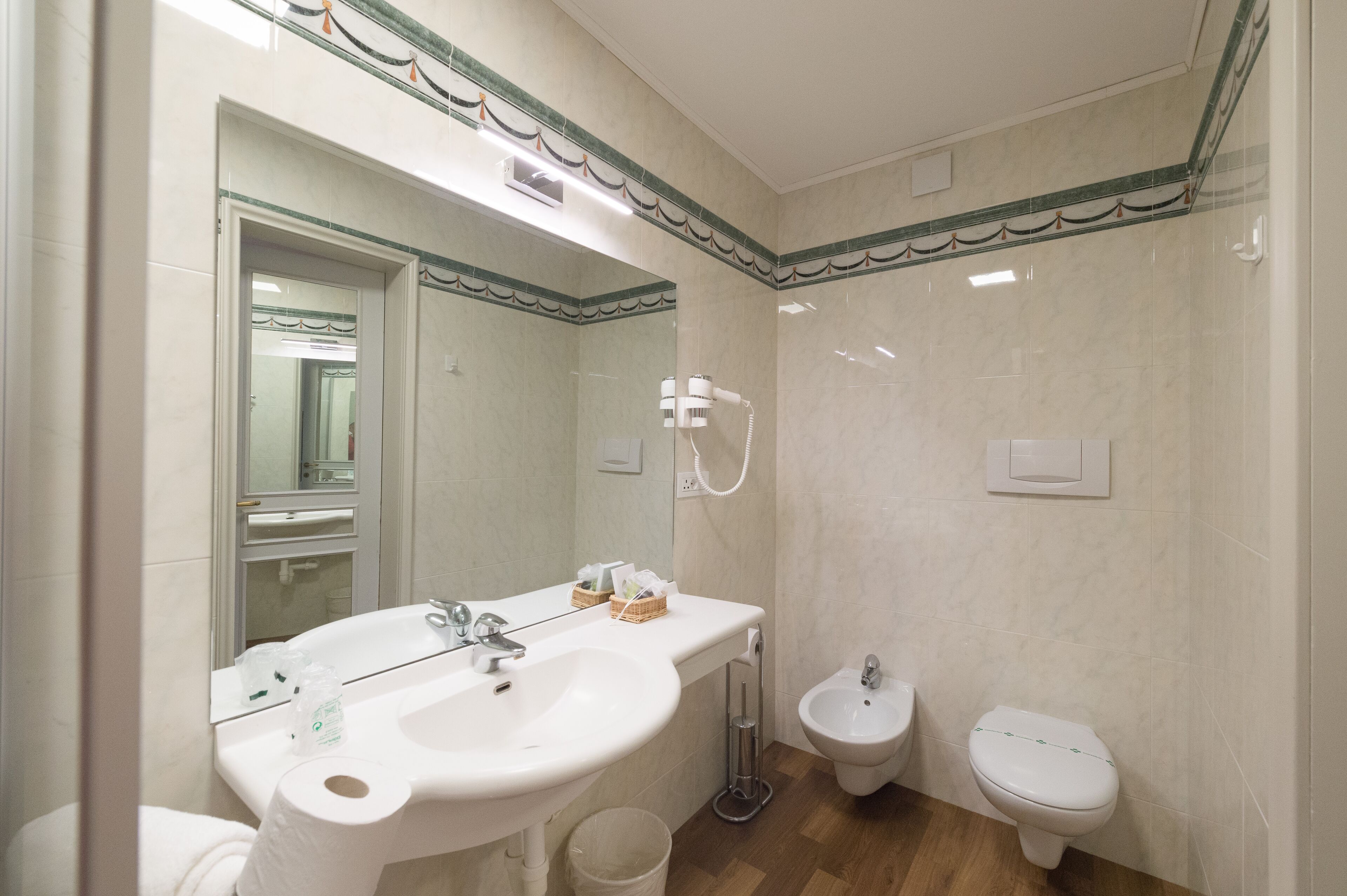 Een badkamer met een wastafel, spiegel, toilet, douchekop en een bidet.