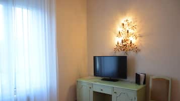 Une pièce comprenant un bureau, un téléviseur, une chaise et un luminaire fixé au mur.