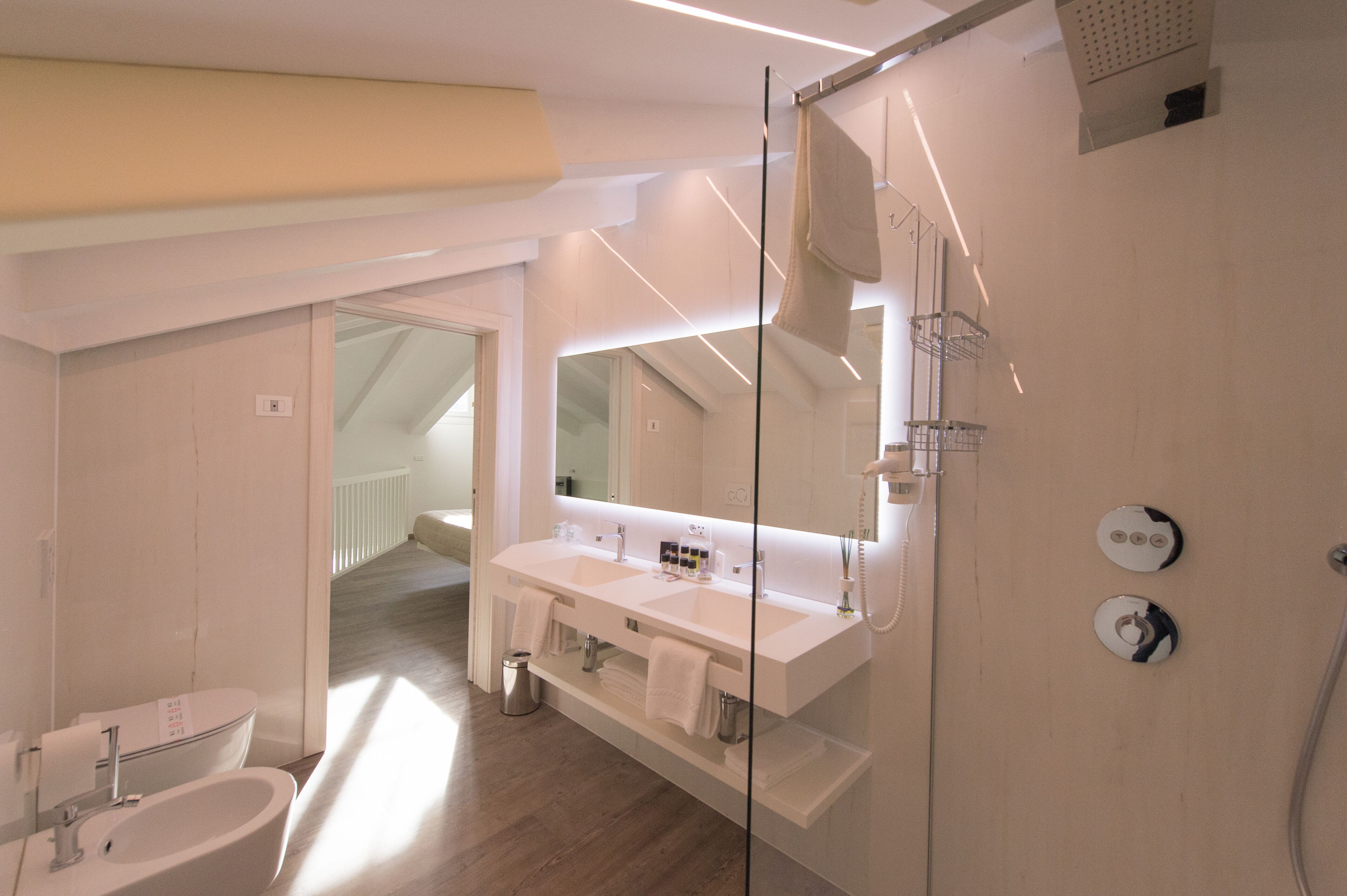 Un baño moderno con un espejo grande, dos lavamanos, ducha y retrete.