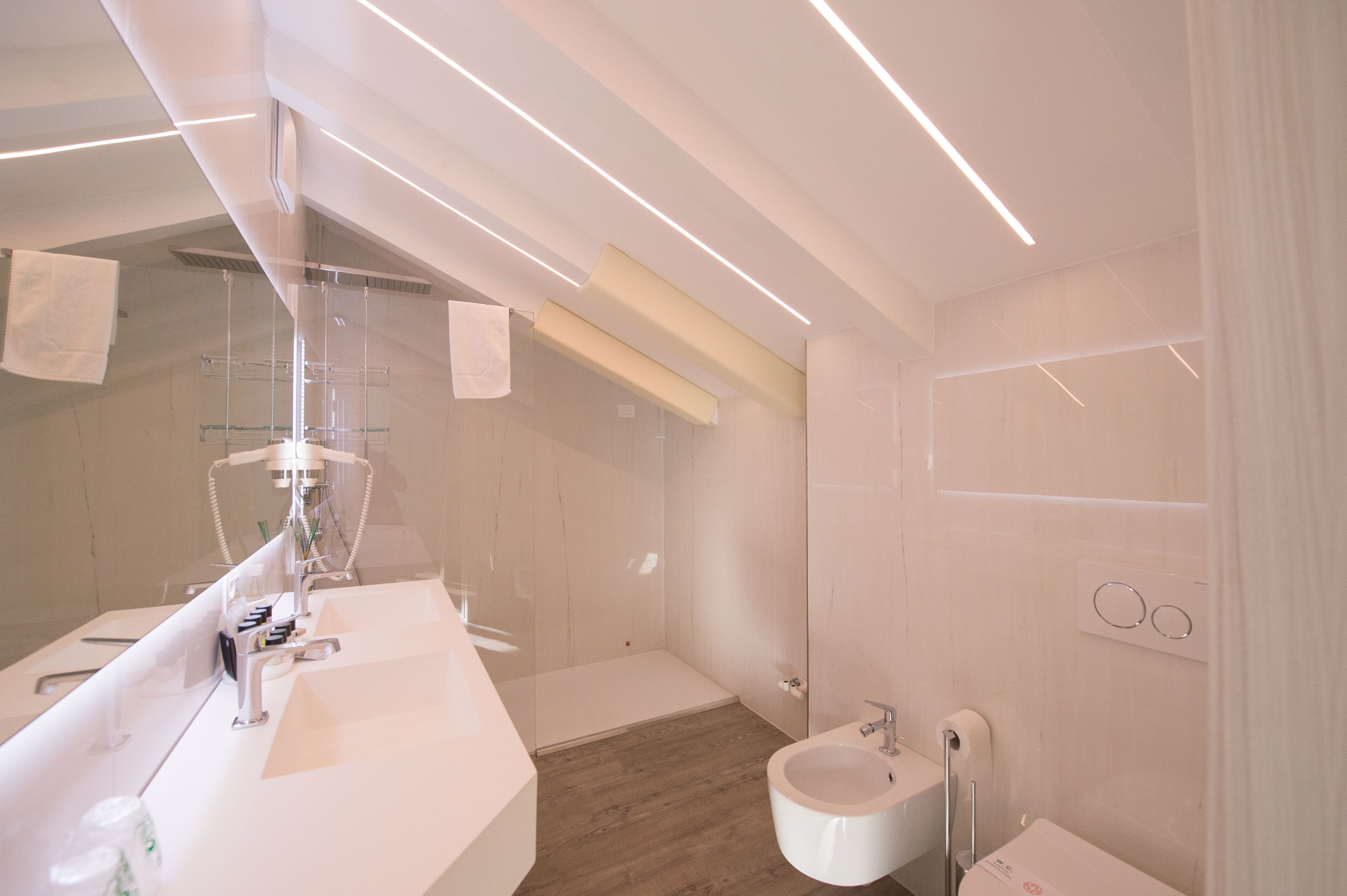 Ein modernes Badezimmer mit einem großen Spiegel, einem Waschbecken, einem Bidet und einer Dusche.