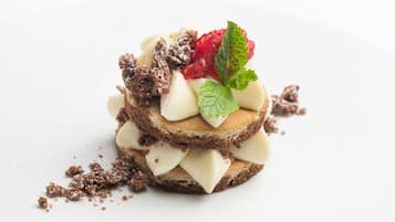 A dessert with layers of cake and cream, garnished with raspberries and mint leaves.